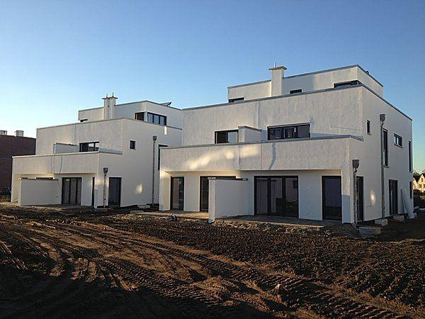 Mehrfamilienhaus, modern, weiß, kubische Architektur, große Fenster, klarer Himmel.