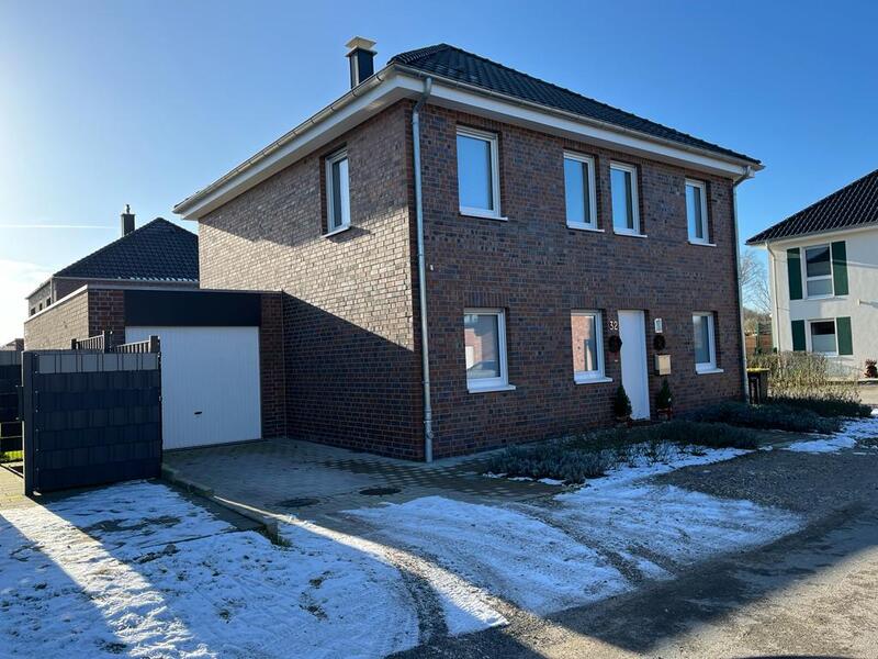 Ein zweistöckiges Backsteinhaus, blauer Himmel, Winterlandschaft, schneebedeckter Boden.