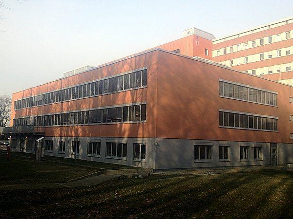 Ein großes, modernes Gebäude mit orangefarbener Fassade und vielen Fenstern bei Tageslicht.