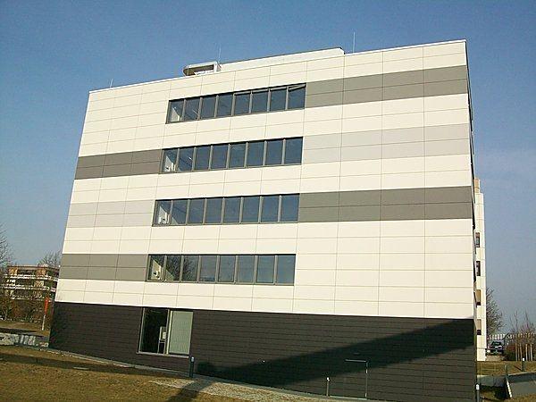 Ein modernes, mehrfarbiges Bürogebäude mit großen rechteckigen Fenstern an klarer Himmel.