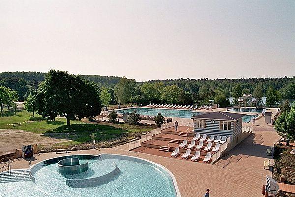 Ein Außenpoolbereich mit Liegestühlen und Bäumen, sonnig, mit wenigen Personen, entspannte Stimmung.