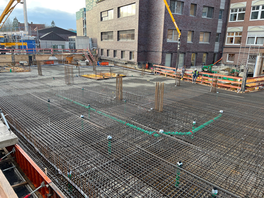 Bauarbeiter auf einer großen Baustelle mit Bewehrungsstahl und Beton zwischen Gebäuden