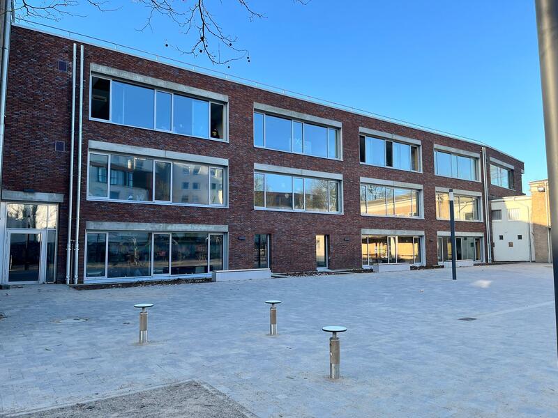 Modernes Backsteingebäude mit großen Fenstern und spiegelndem Glas im Sonnenlicht