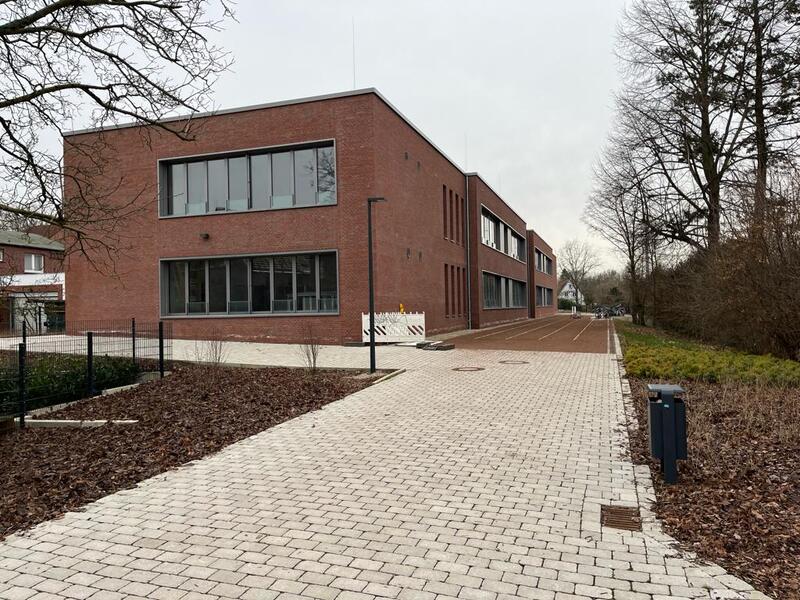 Modernes rotes Backsteingebäude mit großen Fenstern an einem bewölkten Tag