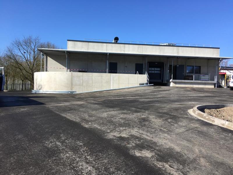 Modern graues Gebäude mit flachem Dach und Rampe vor frisch geteerter Zufahrt