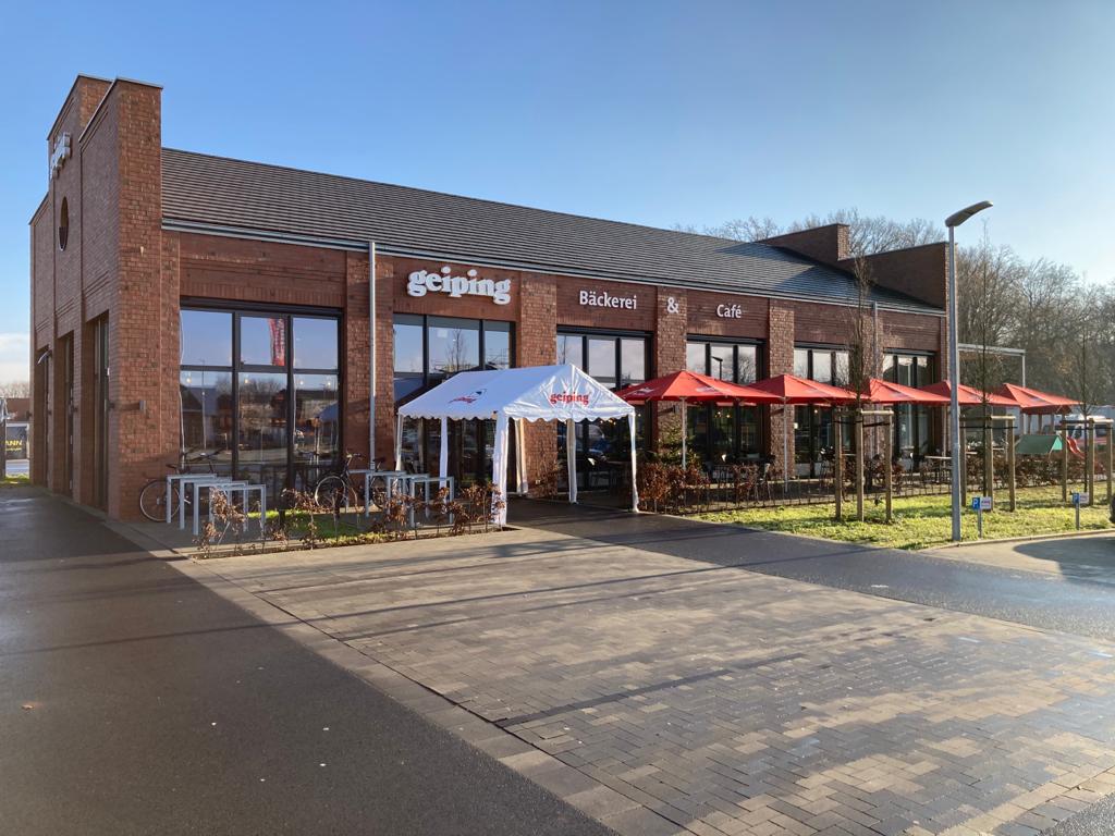 Backsteinbäckerei und Café mit roten Sonnenschirmen an einem sonnigen Tag