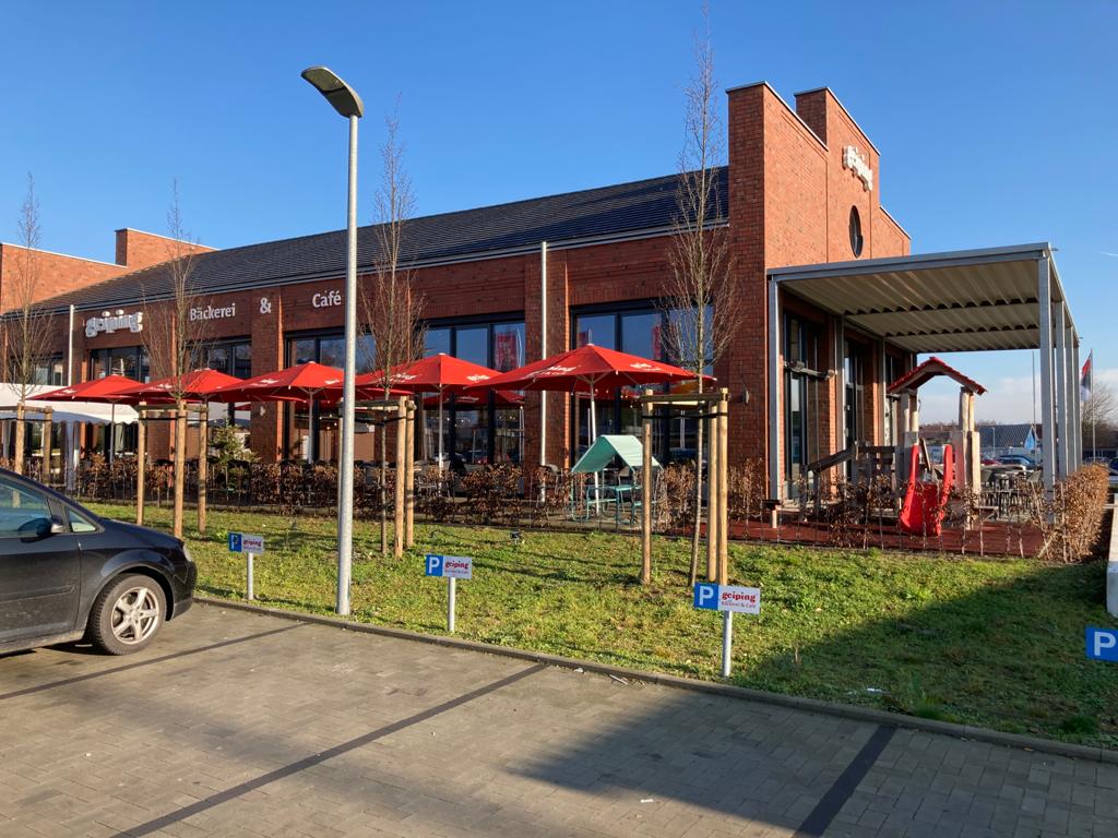 Gemütliches Café mit rotem Sonnenschutz über der Terrasse und freundlicher Atmosphäre