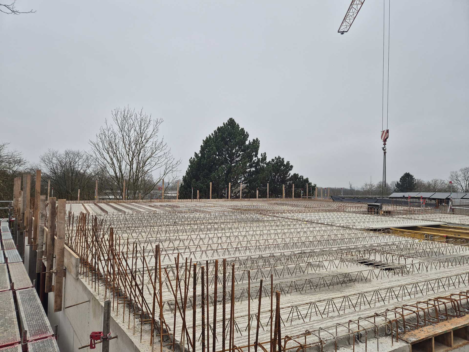 Auf einer Baustelle ist ein Rohbau mit vielen Stahlträgern und grauem Himmel zu sehen