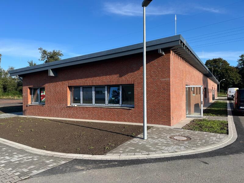 Ein langes rotes Backsteingebäude mit Flachdach und vielen Fenstern bei Sonnenschein