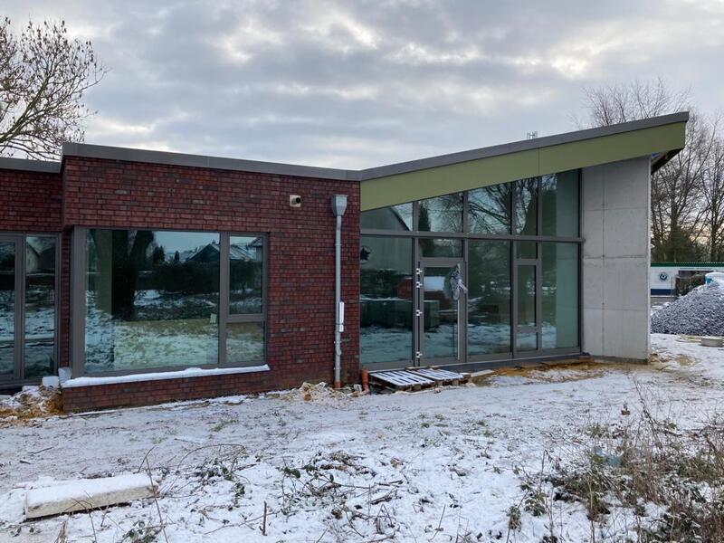 Ein modernes Gebäude mit großen Fenstern, roter Klinkerfassade und Schneebedeckung