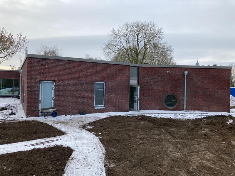Modernes Backsteinhaus mit flachem Dach, runder Fensteröffnung und schneebedecktem Garten