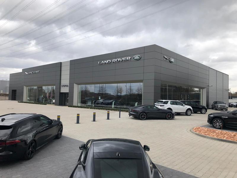 Ein moderner Land Rover Autohaus mit grauer Fassade und mehreren geparkten Autos