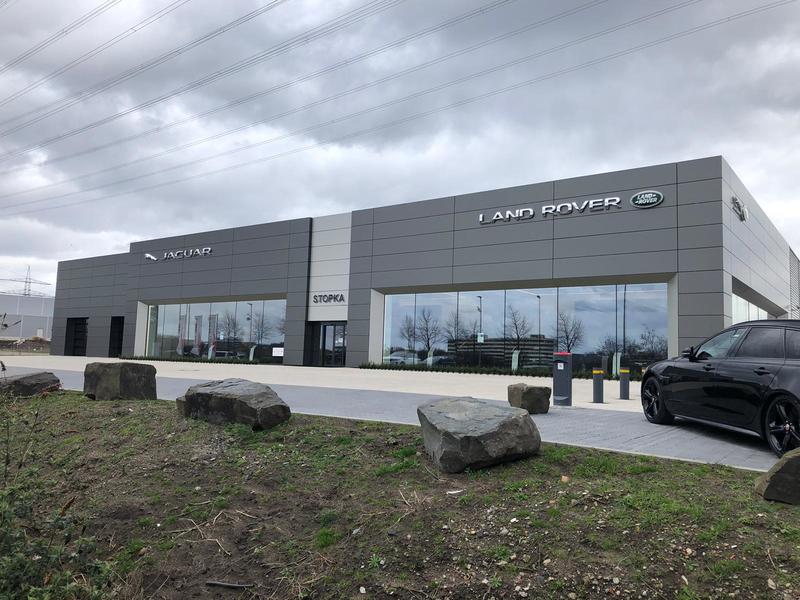 Ein modernes graues Jaguar und Land Rover Autohaus mit großen Glasfenstern und dunklen Wolken
