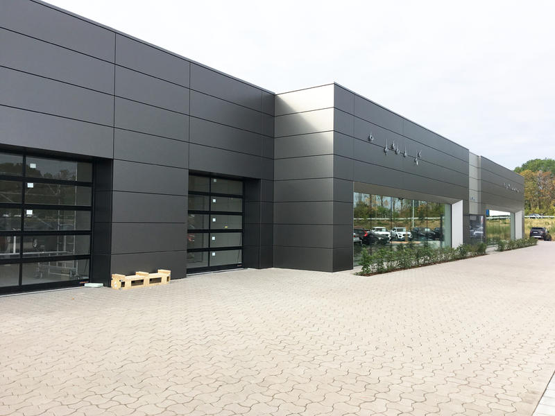 Modernes, graues Firmengebäude mit großen Fenstern und reflektierenden Fassaden