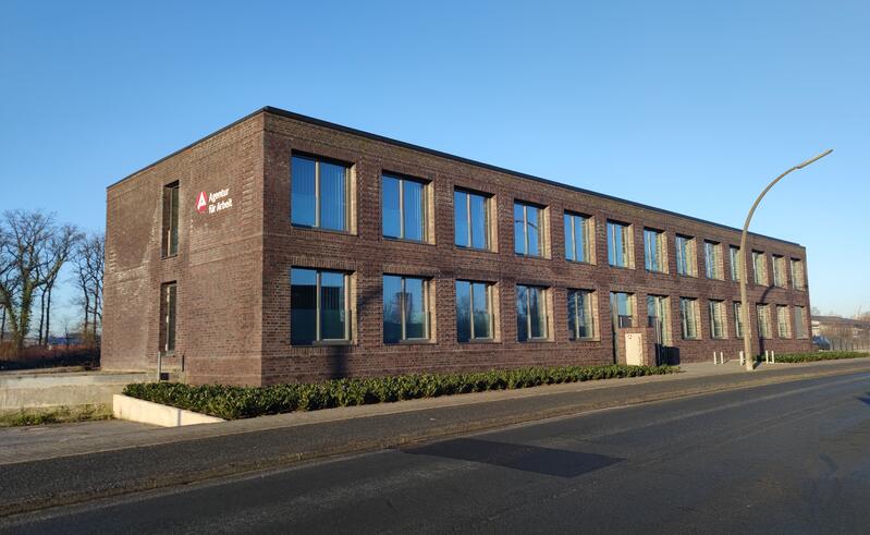 Ein modernes, zweistöckiges Backsteingebäude mit vielen großen Fenstern und blauem Himmel