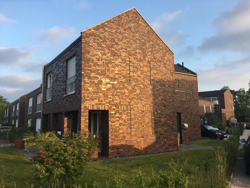 Modernes Einfamilienhaus aus rötlich braunem Backstein in sonnigem Licht