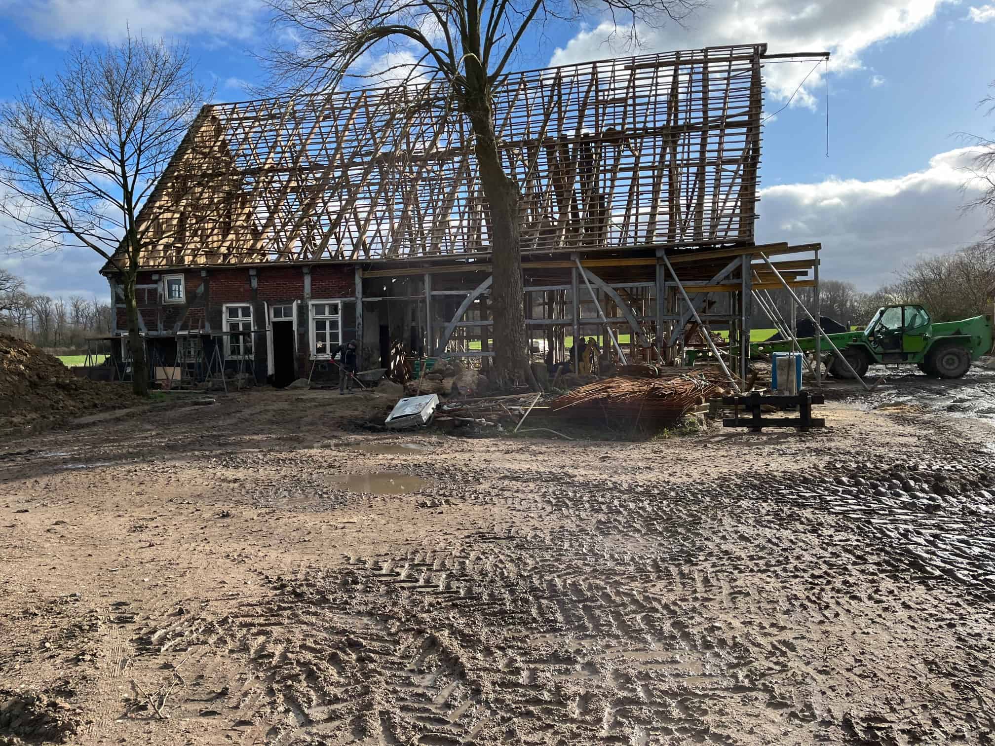Ein Bauernhaus mit entblößtem Holzdach und lehmig schlammigem Boden vor blauem Himmel