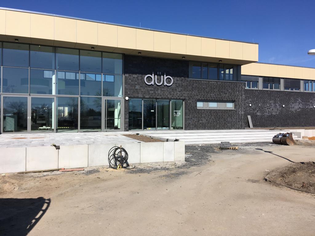 Ein modernes Gebäude mit Glasfassade, beigem Obergeschoss und dem Schriftzug dub