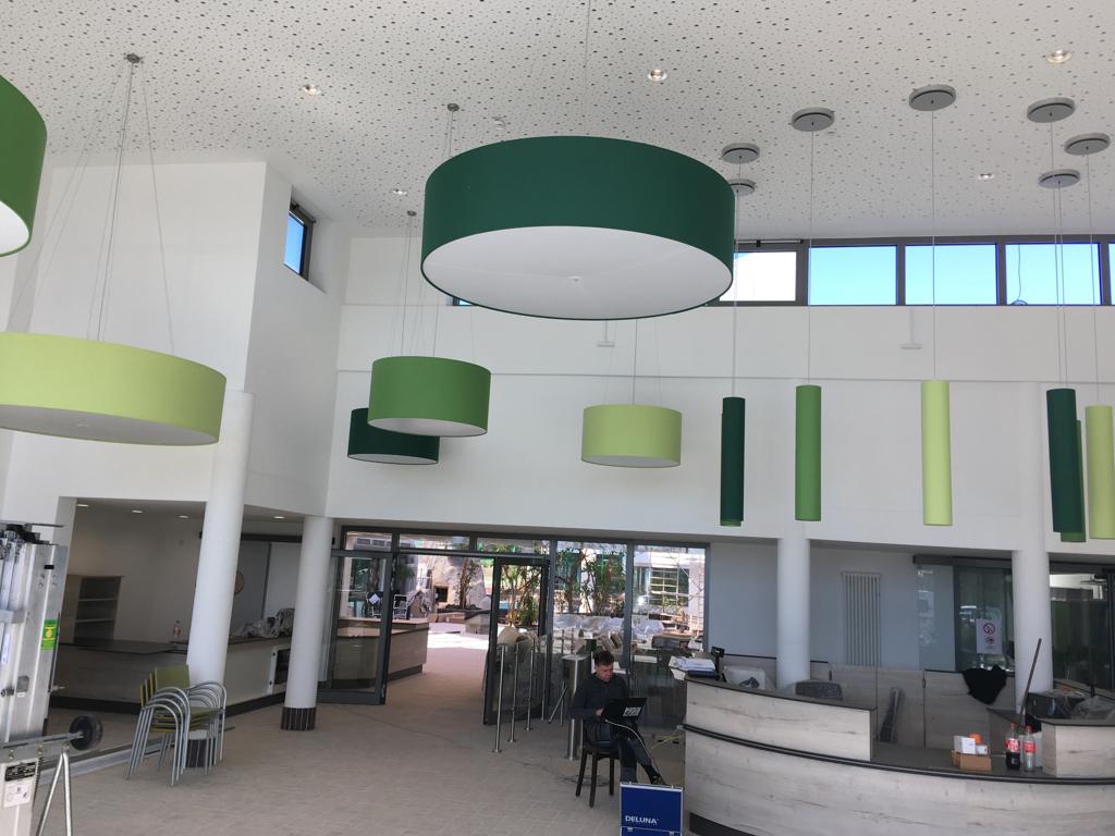 Eine moderne helle Eingangshalle mit großen runden grünen Lampen und Glasfront
