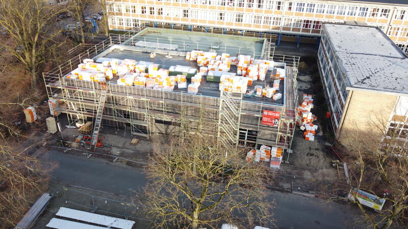 Eine Baustelle mit einem Flachdachgebäude voller orange weißer Materialpakete