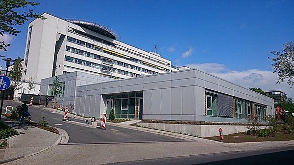 Ein modernes, mehrstöckiges Krankenhausgebäude mit grauer Fassade und Glasfenstern