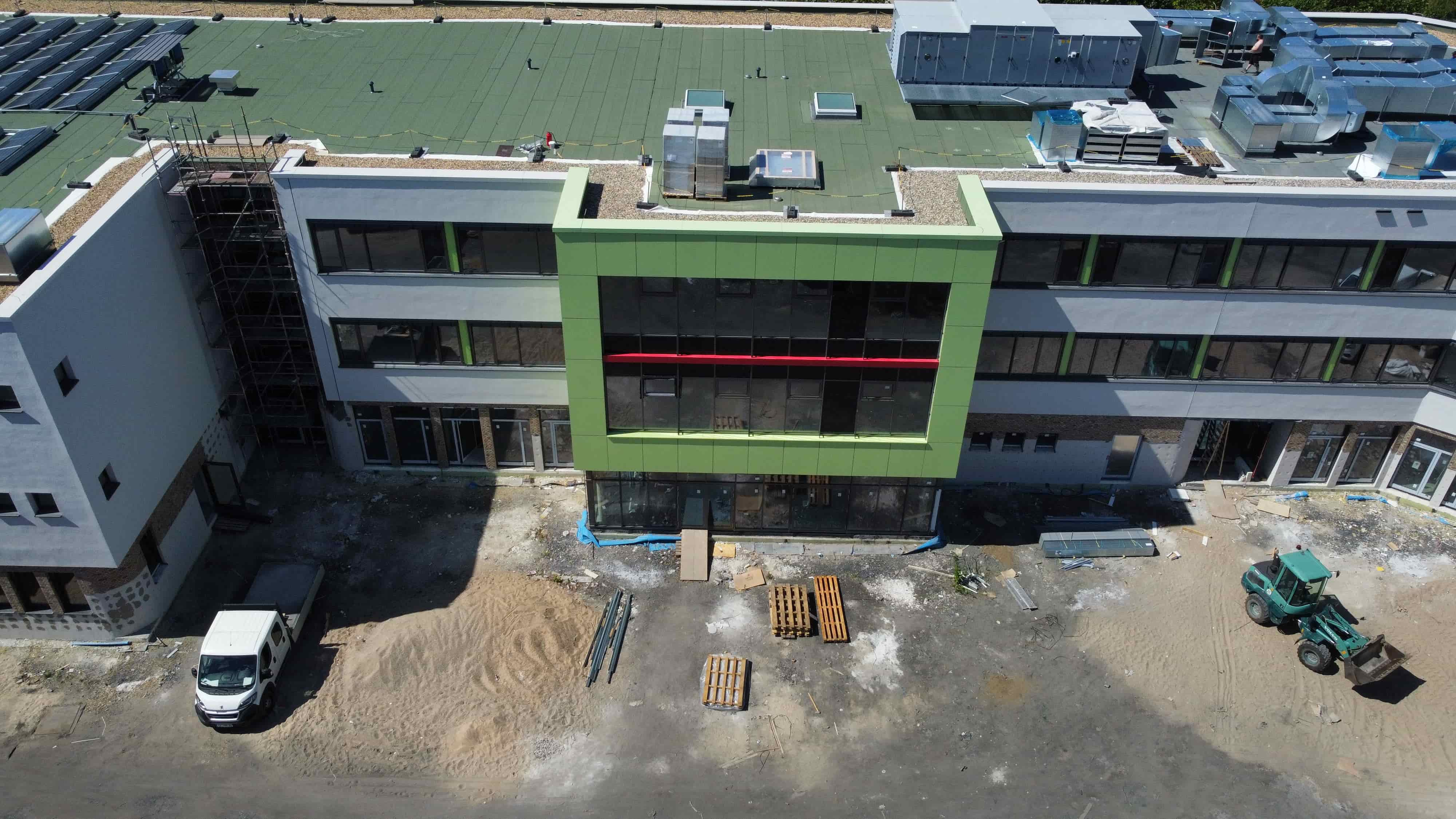 Das Bild zeigt ein modernes Gebäude mit grüner Fassade und dunklen Fenstern