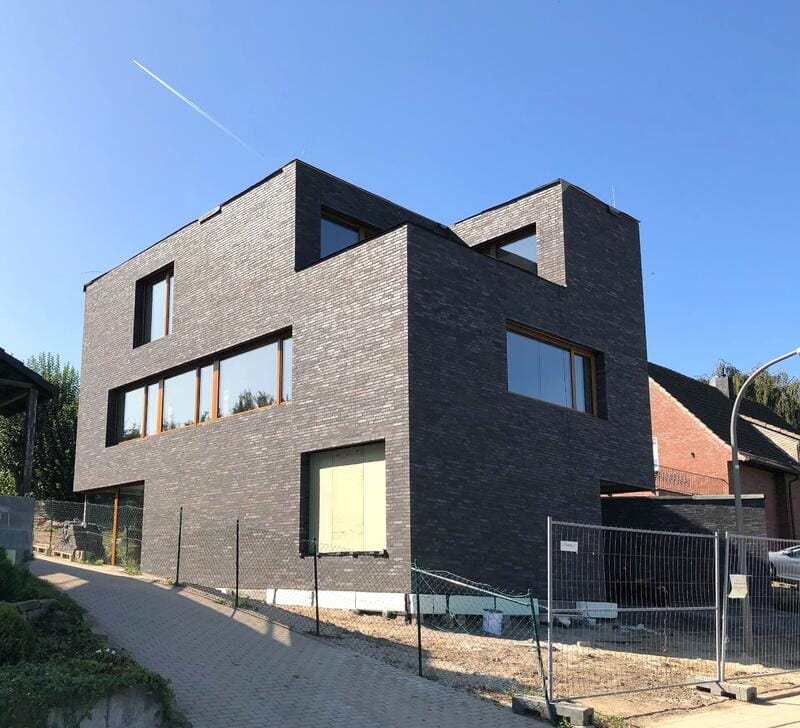 Modernes schwarzes Ziegelhaus mit großen Fenstern und klaren geometrischen Linien