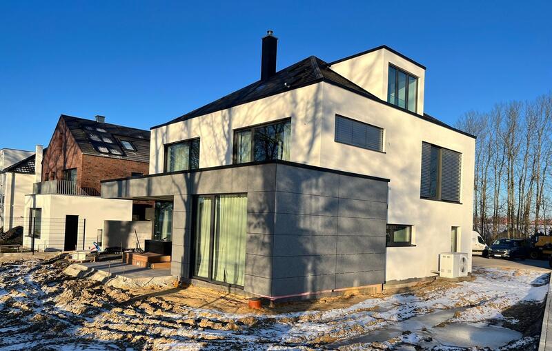 Modernes Einfamilienhaus mit grauer Fassade und großen Fenstern bei sonnigem Wetter