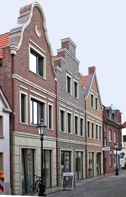 Drei historische Stadthäuser mit Ziegelfassade und typischen Giebeln in warmen Farben
