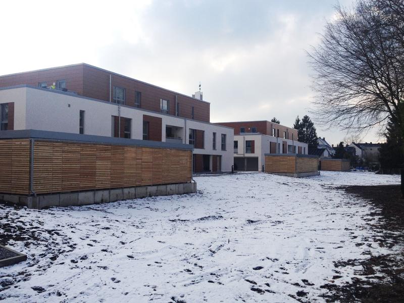 Moderne Wohngebäude mit weißen Fassaden und Holzverkleidung im verschneiten Hof