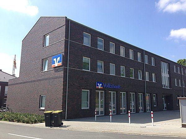 Ein modernes dunkles Gebäude der Volksbank mit großen Fenstern und blauem Himmel
