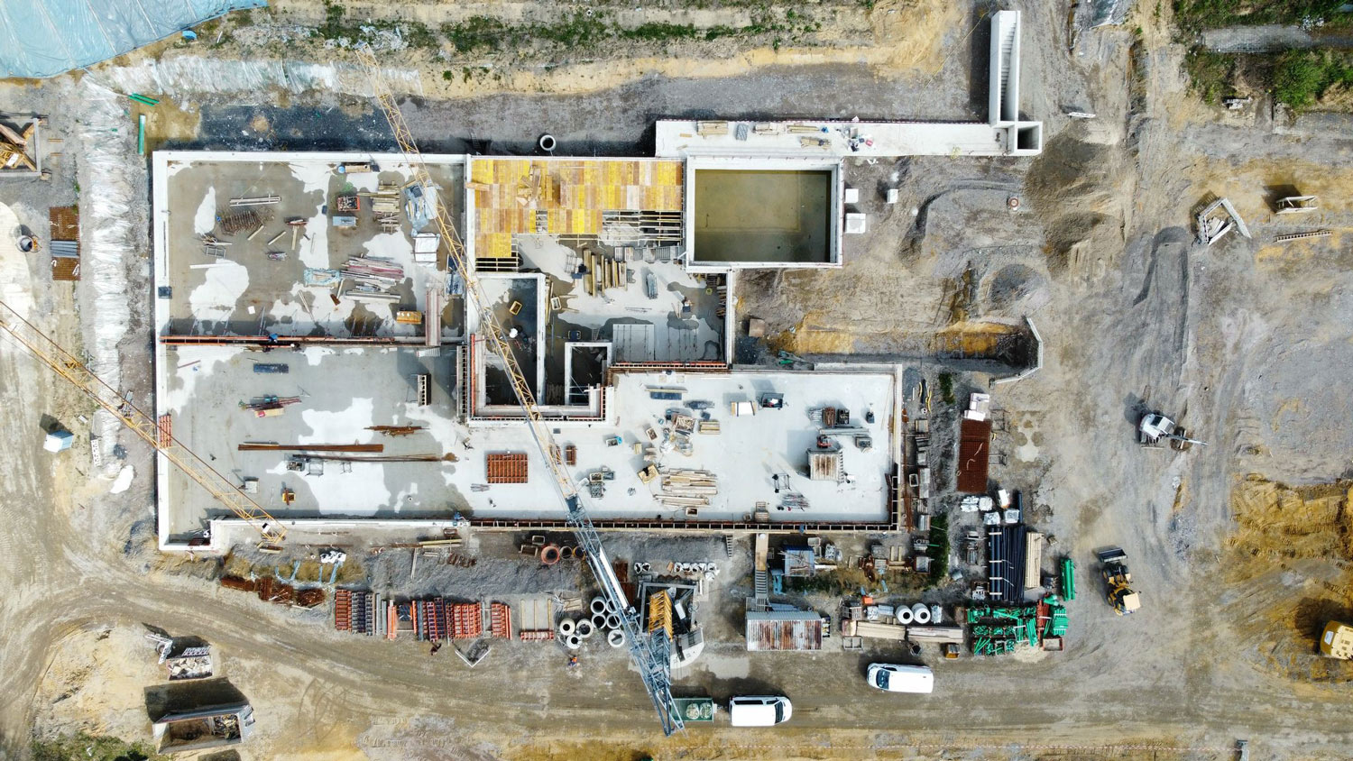 Luftaufnahme einer Baustelle mit hellem Betonboden und verstreuten Baumaterialien