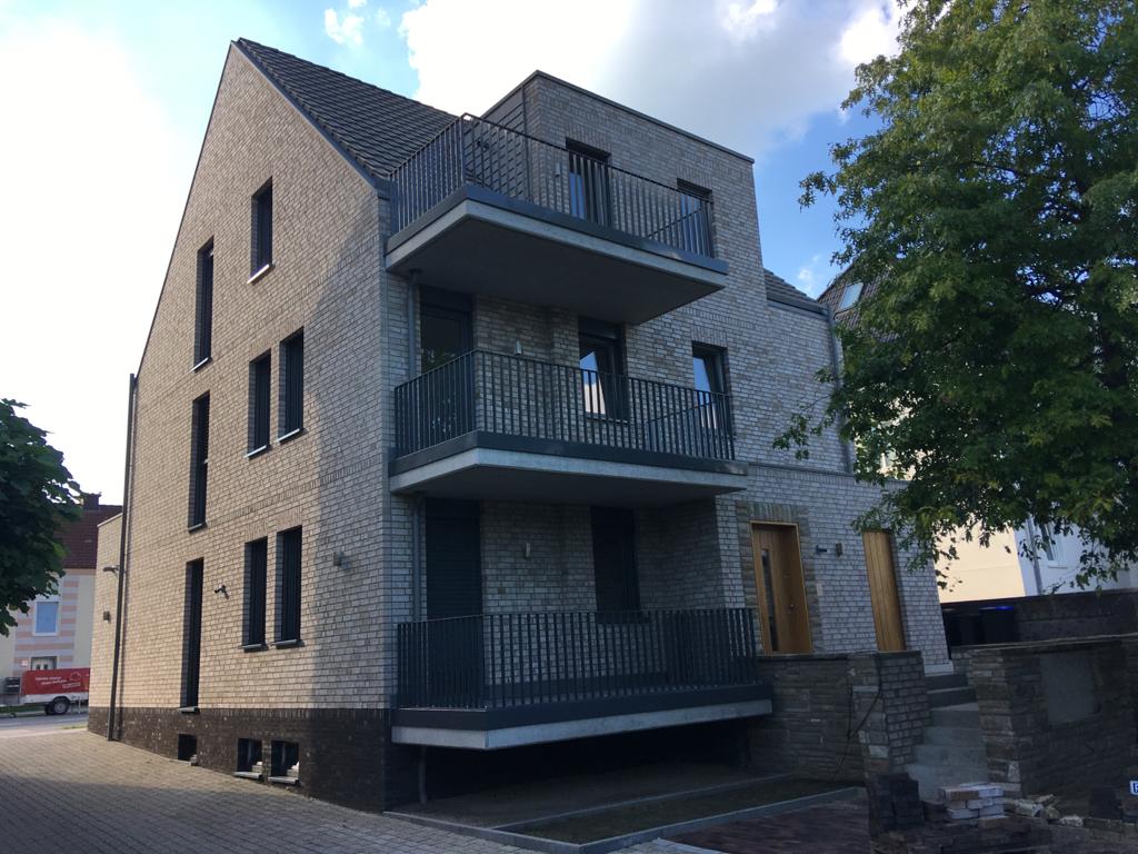 Ein modernes dreistöckiges Wohnhaus aus hellen Steinen mit zwei Balkonen