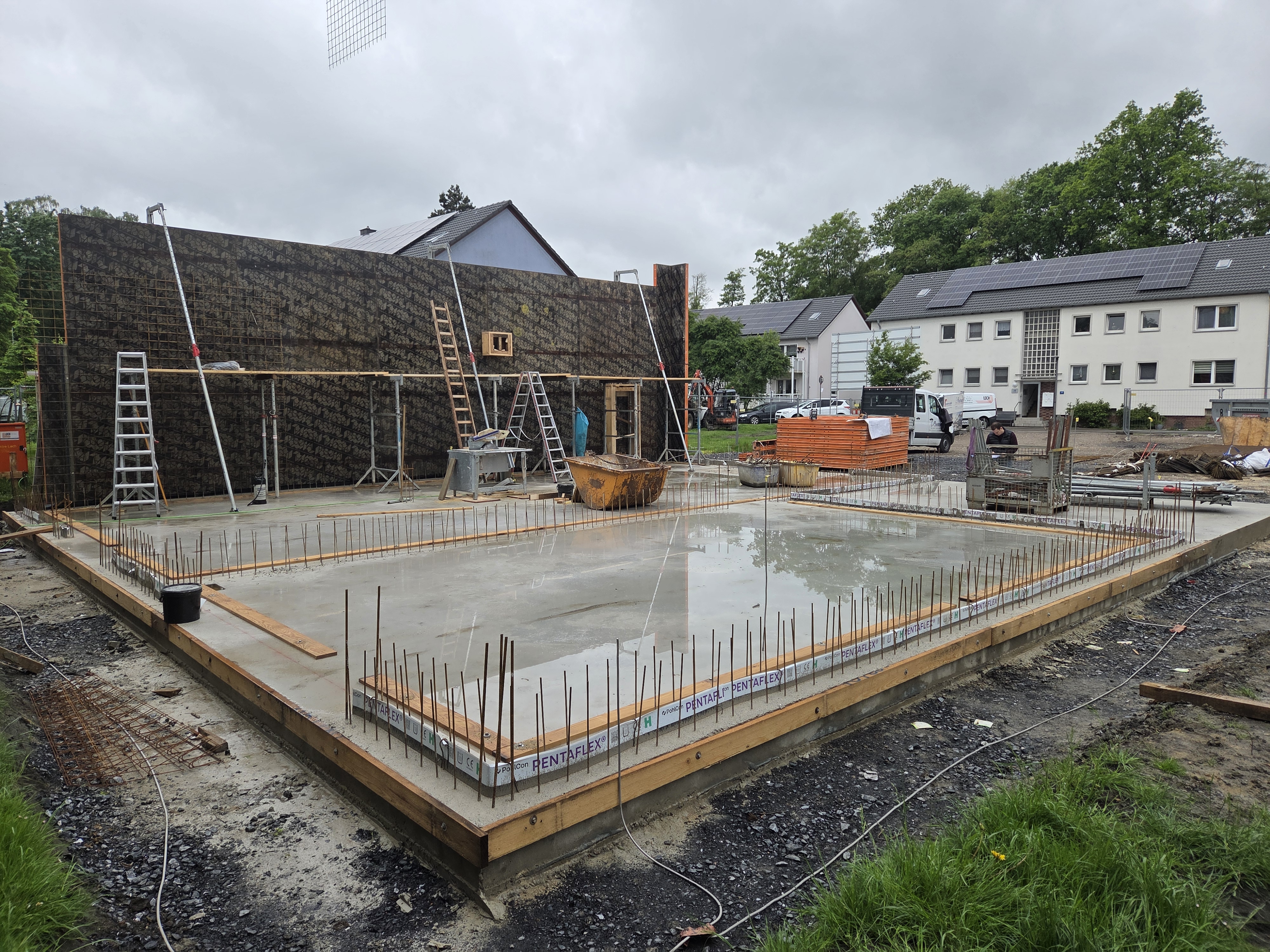 Leere Baustelle mit glatter grauer Bodenplatte, Stahlstäben und Leitern