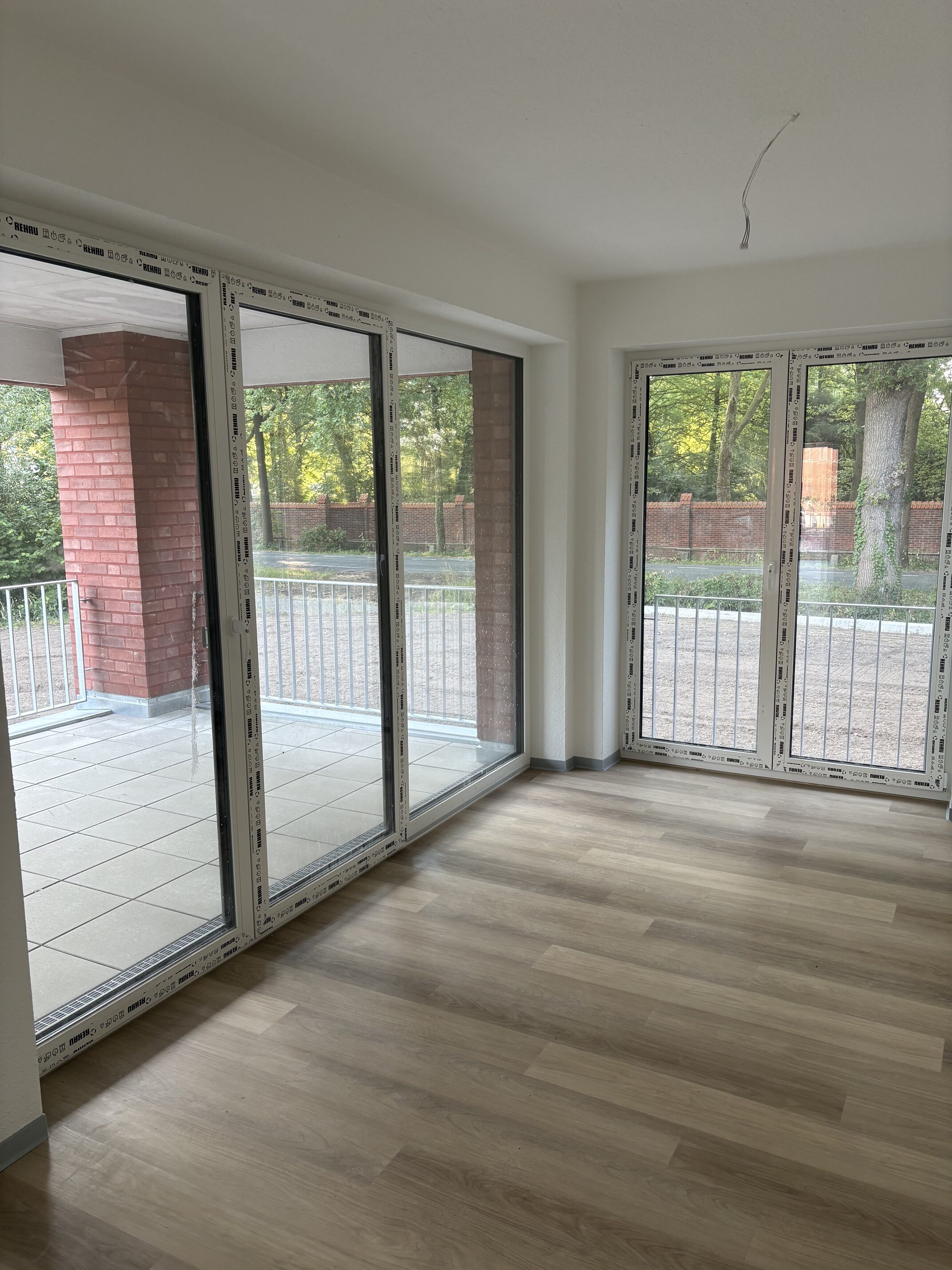 Leerer Raum mit hellen Wanden Holzfussboden und grossen Fenstern